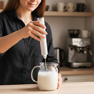 femme mousse lait dans pot de verre avec mousseur a lait